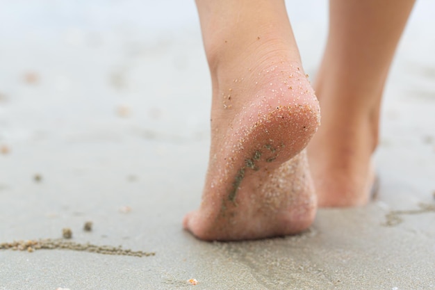 Les pieds d'une jeune femme marchant sur la plage en vacances