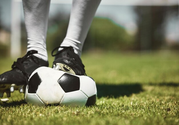 Pieds de joueur de football ballon de football dégonflé et jeu de compétition sportive et entraînement sur terrain en herbe et pelouse