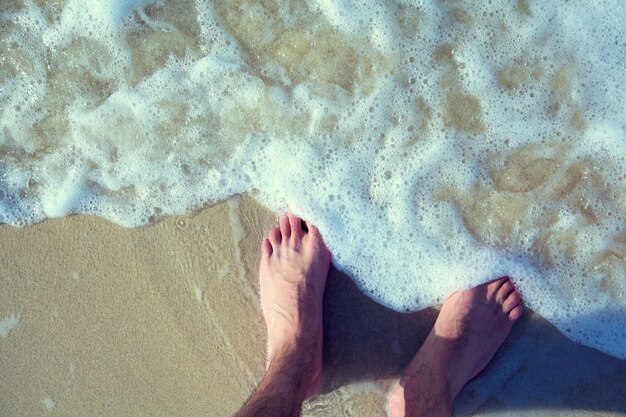 Pieds mâles marchant sur la plage