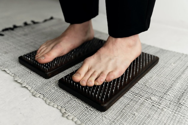 Les pieds masculins se tiennent sur une planche avec des clous. pratique du yoga du matin. planche de sadhu. mode de vie sain. ouverture des chakras. connaissance du Zen.