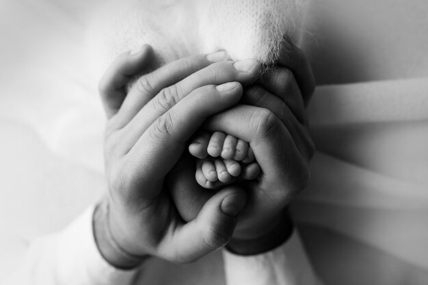 Pieds d'un nouveau-né entre les mains d'un père, parent. Photographie de studio, noir et blanc. Notion de famille heureuse. photo de haute qualité