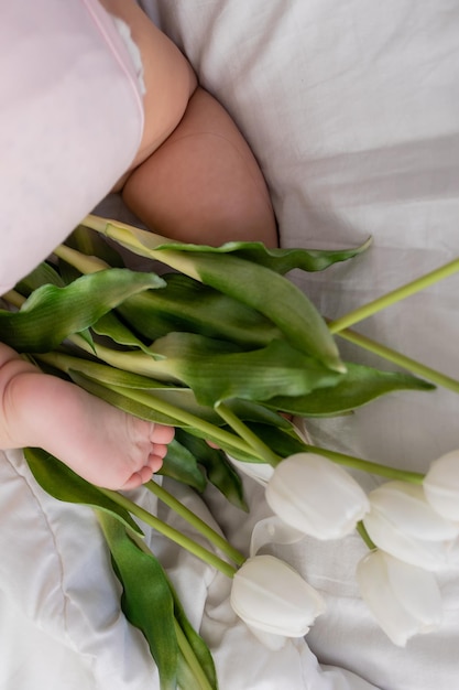 Pieds nus d'un bébé en gros plan de tulipes