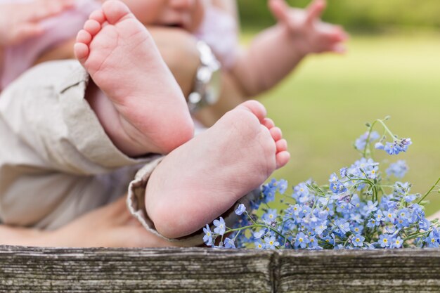 Pieds nus d'un bébé mignon et ne m'oubliez pas des fleurs sur le fond en bois et un enfant