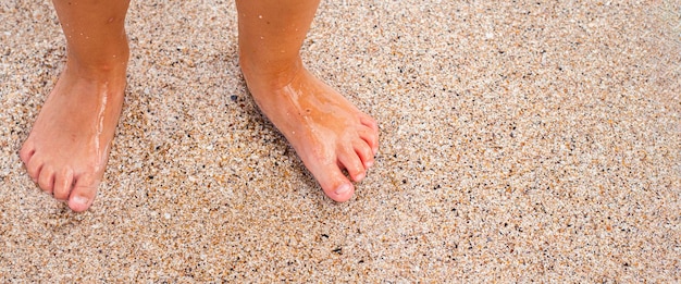 Les pieds nus des enfants se tiennent sur la plage de sable