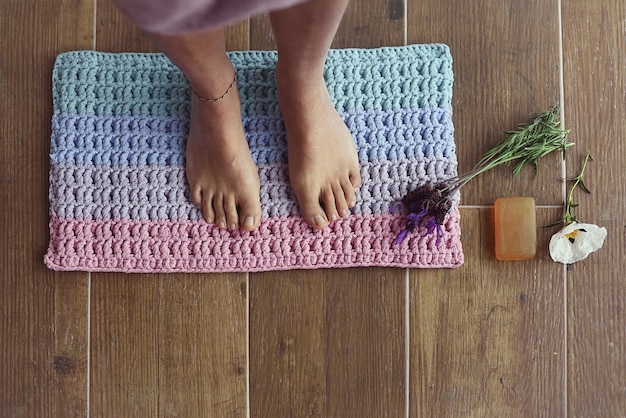 Pieds nus d'une femme sur un tapis de bain avec décorations