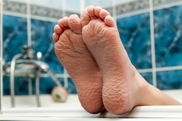 Des pieds nus ridés sortant d'une baignoire.