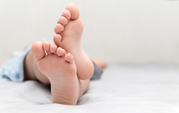 les pieds de la petite fille qui dort dans son lit closeup, confort et concept de relaxation