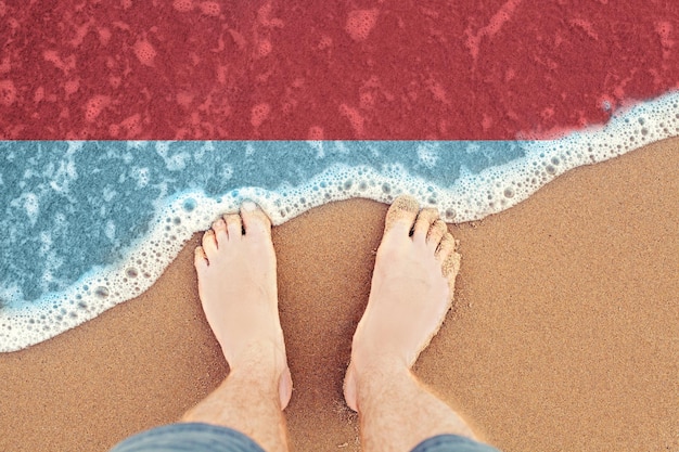 Pieds sur la plage de sable avec drapeau Indonésie Vue de dessus sur les vagues de la mer