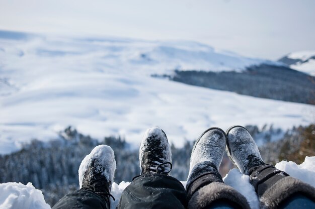 pieds recouverts de neige de deux randonneurs sur un paysage d'hiver