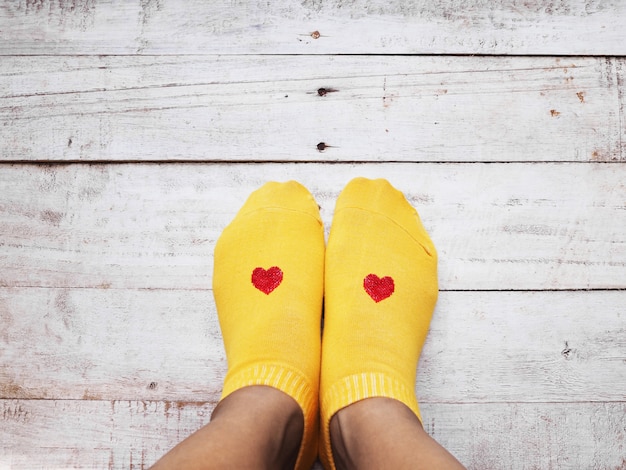 Pieds De Selfie Portant Des Chaussettes Jaunes En Forme De Cœur Rouge Sur Bois