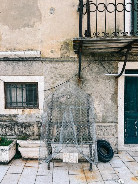 Un piège de pêche traditionnel sèche près d'une vieille maison en pierre.