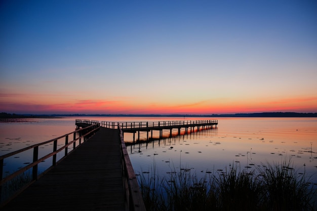 Pier sur le lac contre le ciel au coucher du soleil
