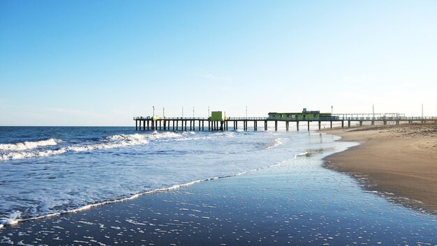 Photo pier sur la plage contre un ciel dégagé