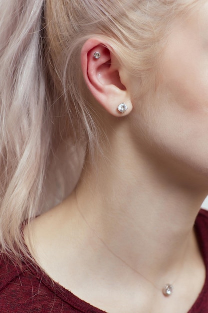 Piercings sur une oreille Piercings de conque et d'hélice en gros plan Professionnel tenant le bijou