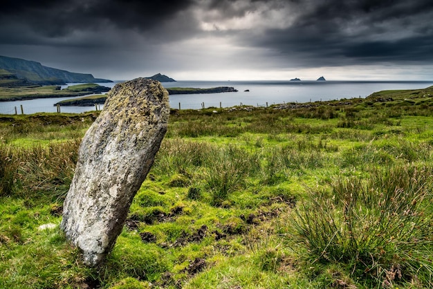 Une pierre dressée sur la côte de l'île de Valentia fait face aux îles Skellig à Kerry, en Irlande