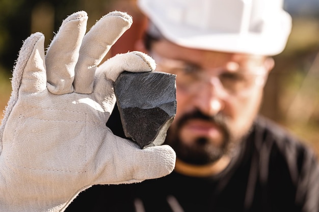 Photo pierre de fer brut pépite de métal ferreux extrait miner holding pierre d'hématitie spot focus