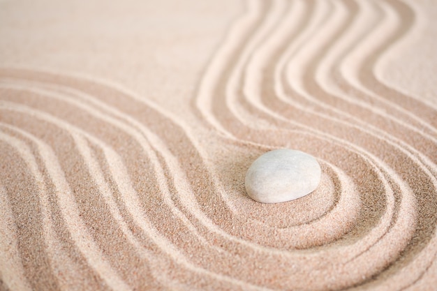 Photo pierre de jardin zen japonais sur la plage de sable des vagues. rocher ou cailloux avec espace de copie. pour le spa d'aromathérapie pendant les vacances d'été. méditation bien-être et tranquillité concept japonais.