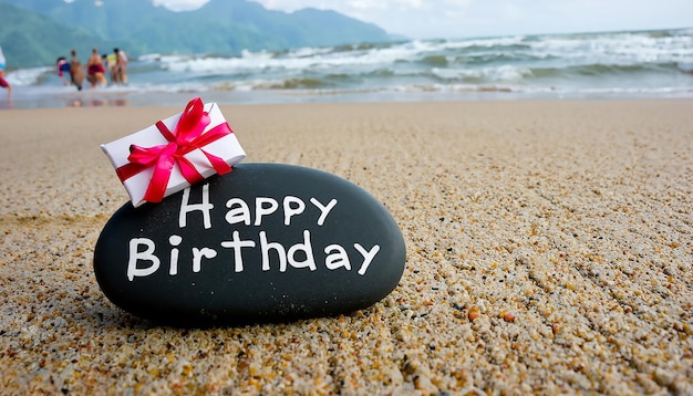 Pierre de joyeux anniversaire sur une plage de galets face à la fête d'anniversaire de la mer en vacances