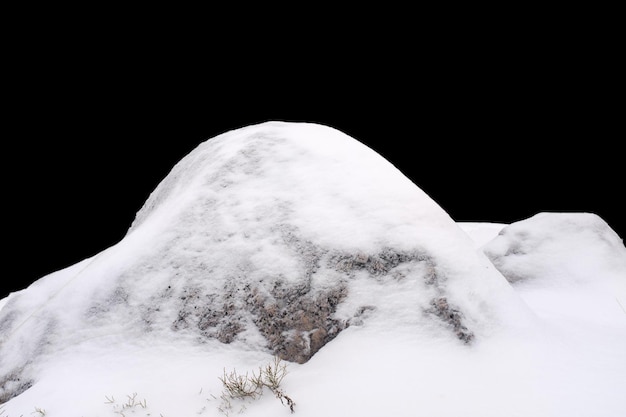 Pierre naturelle dans la neige isolée sur fond noir Photo de haute qualité