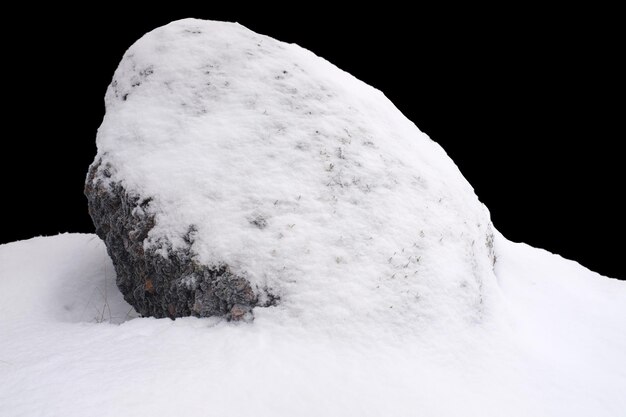 Pierre naturelle dans la neige isolée sur fond noir Photo de haute qualité