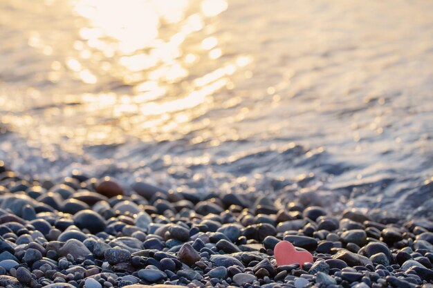 pierre rouge en forme de cœur sur la plage par la mer