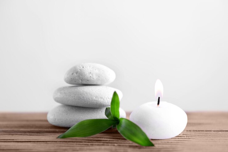 Photo des pierres blanches de spa avec une bougie sur un fond clair