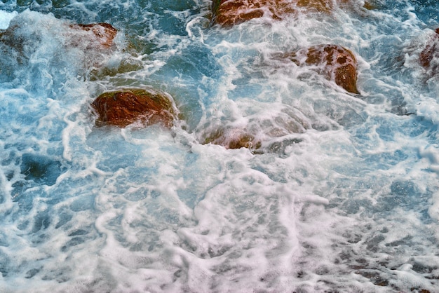 Pierres brunes sous l'écume de mer blanche pour un fond texturé naturel abstrait