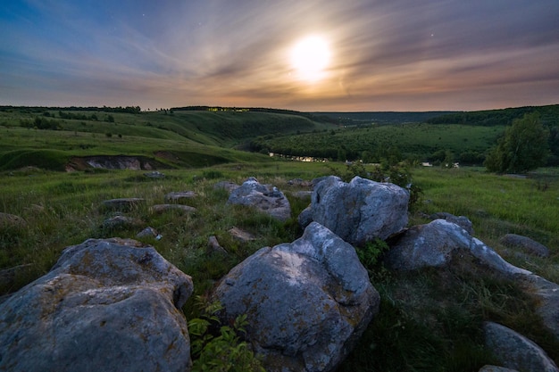 Pierres glaciaires de nuit dans le paysage de champ sous le halo de clair de lune