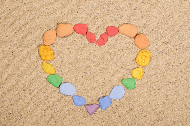 Pierres multicolores disposées en forme de coeur sur le sable