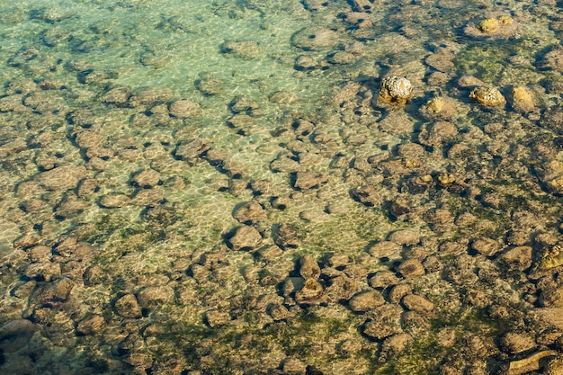 Pierres sous la texture de fond de la lumière du soleil de l'eau