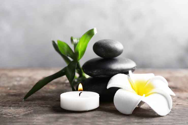 Photo pierres de spa avec bougie bambou et fleur tropicale sur table en bois sur fond gris