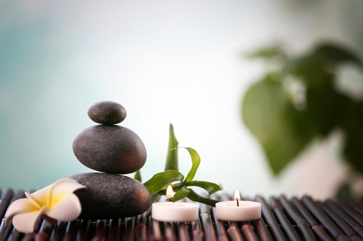 Photo pierres de spa avec bougies et fleurs tropicales sur fond flou