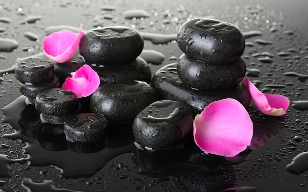 Pierres de spa avec gouttes et pétales de rose sur fond gris