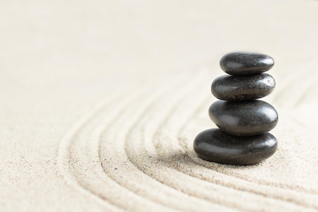 Photo pierres zen noires dans une pile sur le sable de la plage fond de pierre de méditation