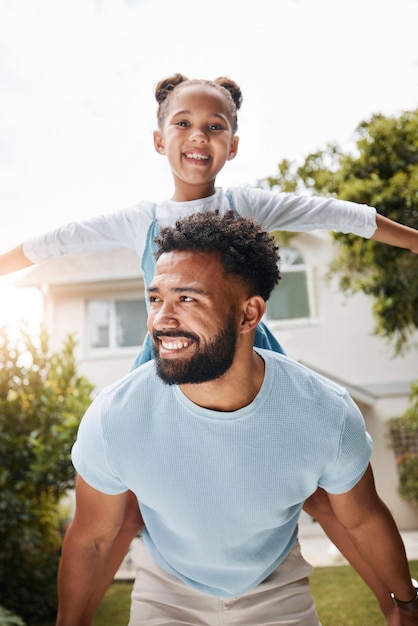 Photo piggyback ludique et jeune père avec son enfant se liant à l'extérieur dans le jardin à la maison heureux homme et sa fille profitant de temps de qualité ensemble jeune fille souriante et homme jouant dehors au printemps