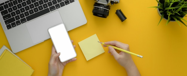 Pigiste à l'aide d'un smartphone sur un bureau jaune