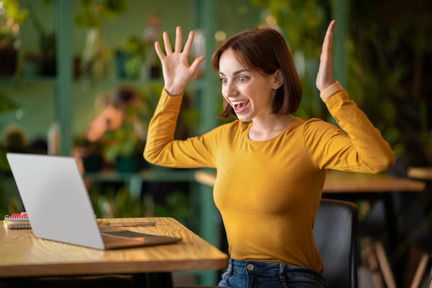 Pigiste émotionnelle de jeune femme utilisant un ordinateur portable au café