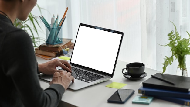 Pigiste de jeune homme travaillant avec un ordinateur portable au bureau à domicile.