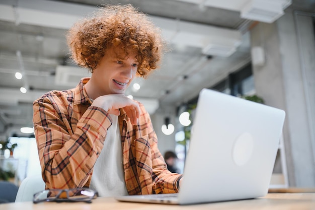 Un pigiste masculin élégant travaillant sur un nouveau projet de démarrage permettant aux chercheurs d'Internet d'analyser des données à l'aide d'un ordinateur portable