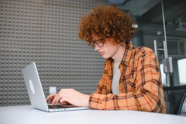 Un pigiste masculin élégant travaillant sur un nouveau projet de démarrage permettant aux chercheurs d'Internet d'analyser des données à l'aide d'un ordinateur portable