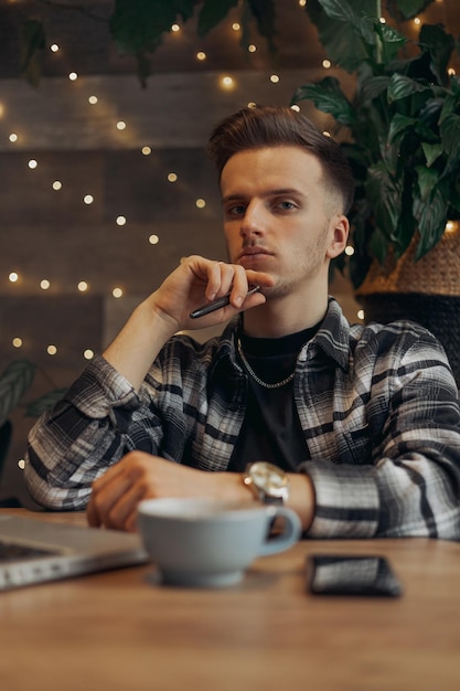 Pigiste masculin sérieux travaillant dans un café et regardant la caméra