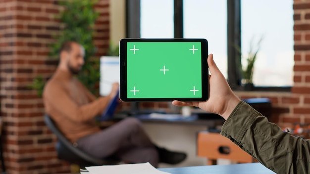 Pigiste masculin tenant un écran vert horizontal sur un gadget numérique, à l'aide d'une tablette avec un modèle de maquette vierge et un fond de clé chroma isolé. Travailler avec l'arrière-plan de l'affichage de l'appareil.
