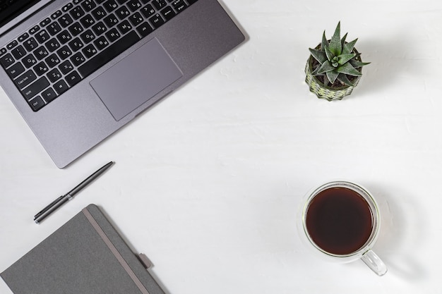 Pigiste en milieu de travail. Ordinateur portable moderne gris avec clavier russe, tasse de café, stylo métallique