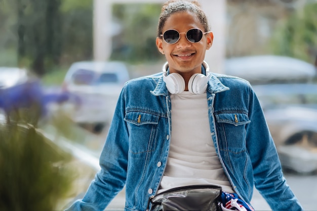 Un pigiste à la peau foncée heureux portant des lunettes élégantes tout en regardant la caméra