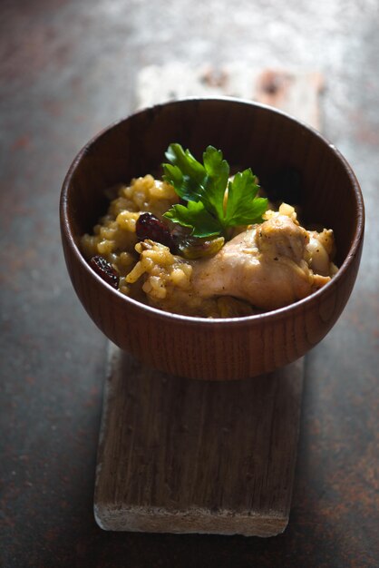 Pilaf au riz poulet et raisins secs dans un bol en bois