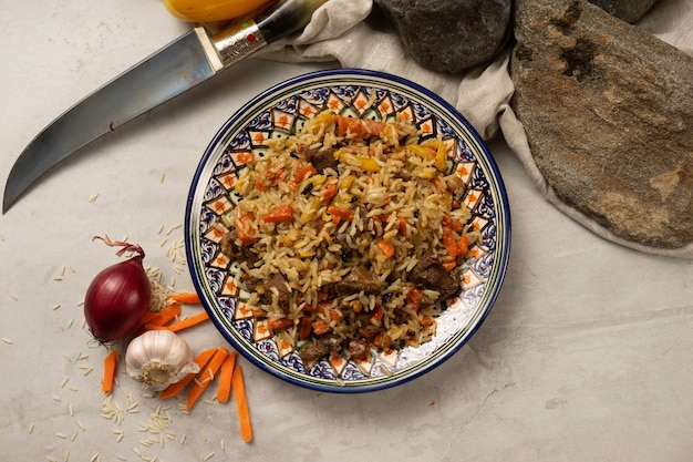 Pilaf chaud avec de l'agneau ou du bœuf dans une assiette nationale ouzbèke décorative avec un motif traditionnel.