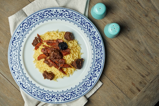 Pilaf léger, régime avec du boeuf et des carottes sur une plaque blanche sur une surface en bois. Vue de dessus avec espace de copie pour le texte. Cuisine orientale traditionnelle