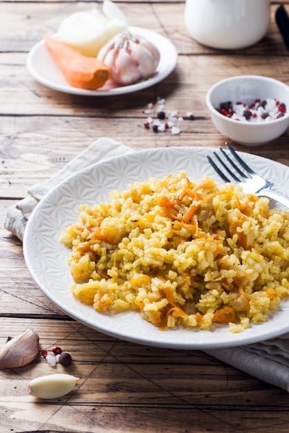 Pilaf oriental végétarien avec du riz et des légumes sur une table en bois.