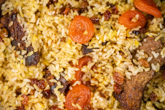 Pilaf avec de la viande, des abricots secs et des raisins secs en arrière-plan