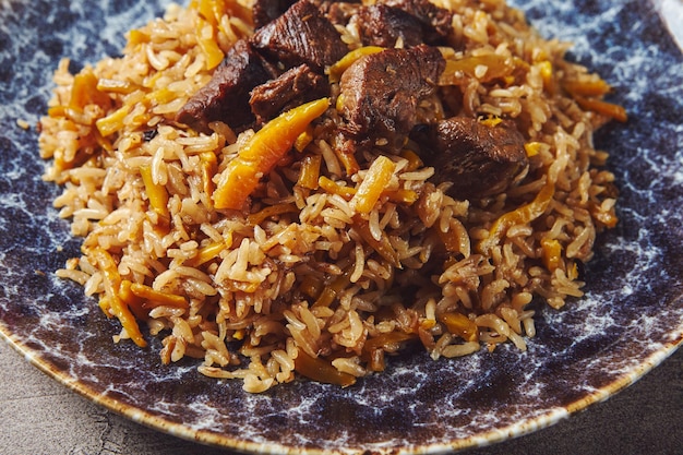 Pilaf à la viande d'agneau dans une grande assiette de salade de tomates et plat de légumes et de légumes verts